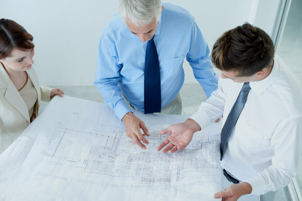 three people standing around a giant city planning document